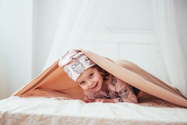 Adorable baby girl, looking out under a towel