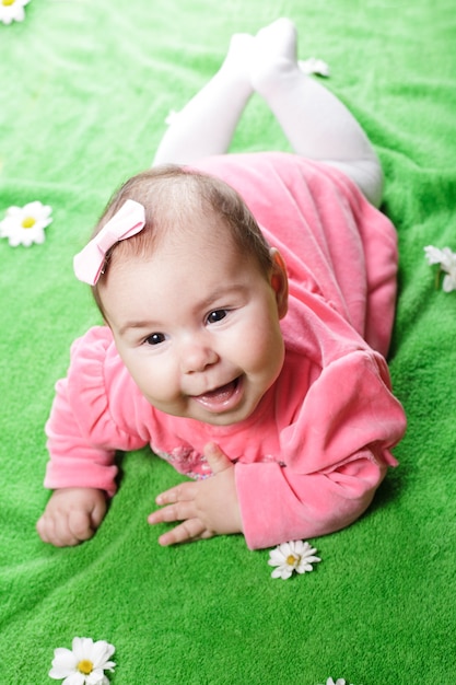 Adorable baby girl lying down on meadow and smile