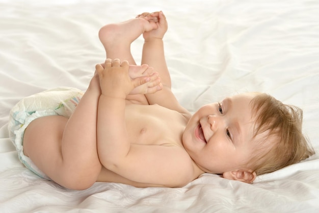 Adorable baby girl lying in pampers on blanket on a white background