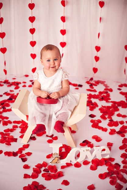 写真 ギフトの赤いハートとバラの花びらのバレンタインデーのコンセプトを持つ愛らしい女の赤ちゃん