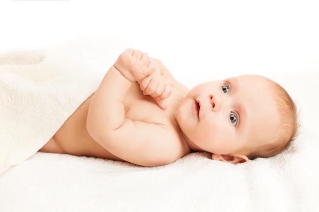 Adorable baby lying on white sheets.