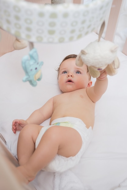 Photo adorable baby playing with toys in crib