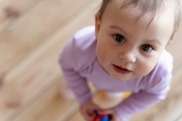 Foto bambino adorabile che posa e gioca con il giocattolo sul pavimento