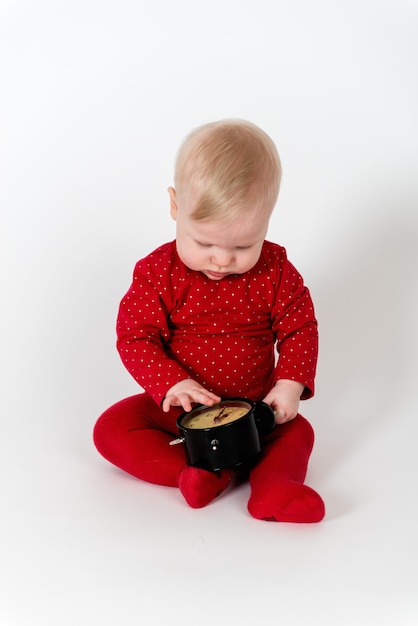 Adorable baby in red suite sitting and looking on the clock