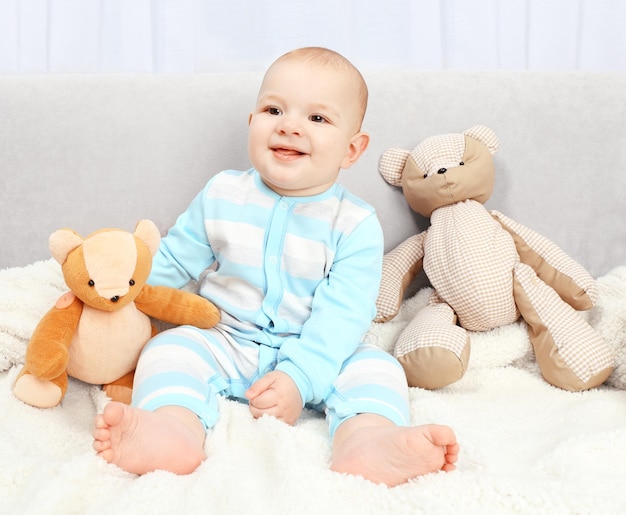 Adorable baby with teddy bears on sofa in the room close up