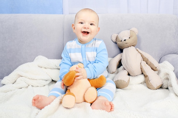 Adorable baby with teddy bears on sofa in the room close up