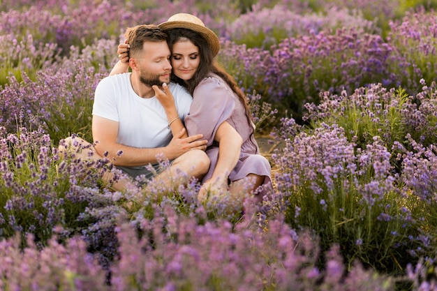 Adorable beautiful couple sitting in the lavender field hugging enjoying moments together