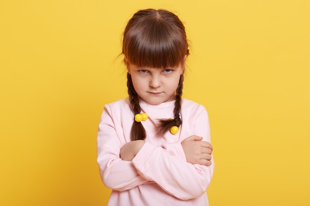 Adorable beautiful little offended girl over yellow