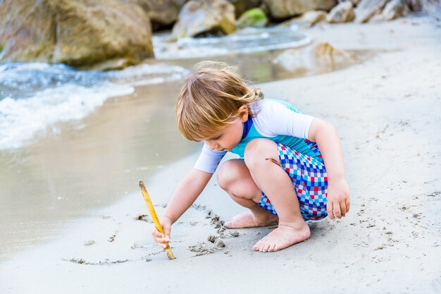 愛らしい金髪の幼児の男の子が海辺のビーチで遊ぶ