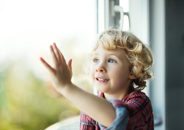 窓の外を見ている愛らしい金髪の幼児の女の子