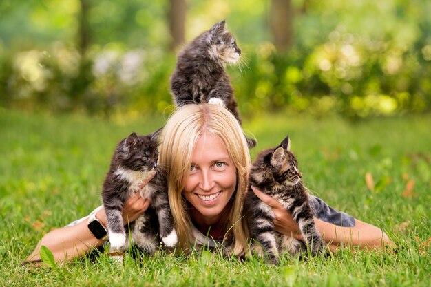 Adorable blonde girl playing with little kittens on warm and sunny summer day