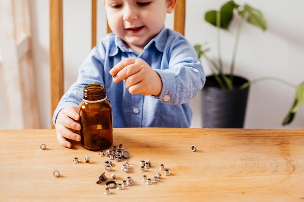 愛らしい男の子は瓶の中の金属ボタンを埋めます