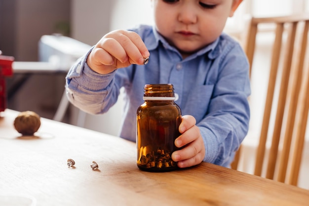 愛らしい男の子は瓶の中の金属ボタンを埋めます