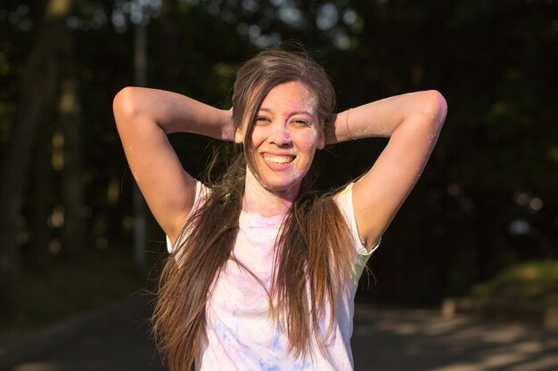 Adorable brunette asian woman having fun with Holi paint exploding around her