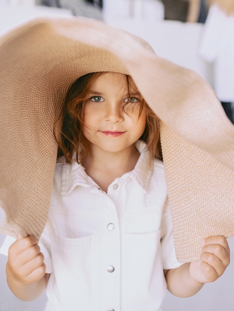 Фото Очаровательная веселая маленькая девочка в соломенной шляпе дома в помещении