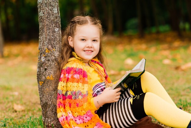 Adorable child girl at a beautiful autumn park