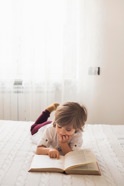 Foto bambino adorabile che legge la bibbia a casa