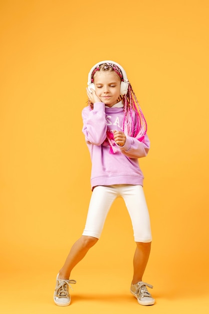 Adorable child in rounded glasses with pink dreadlocks listen to