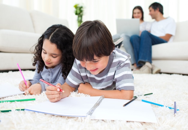 Adorable children drawing lying on the floor 