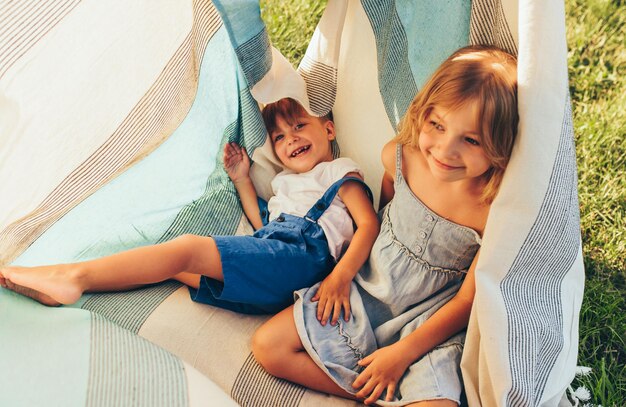 Фото Очаровательные дети, сестра и брат, играющие на одеяле счастливый маленький мальчик и маленькая девочка наслаждаются летним днем на отдыхе в парке откровенный снимок детей, играющих на открытом воздухе