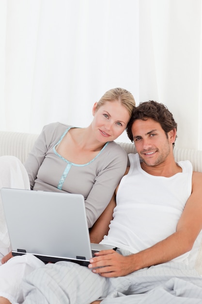 Adorable couple looking at their laptop on the bed 