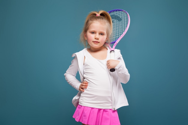 Фото Очаровательная милая маленькая девочка в белой рубашке, белой куртке и розовой юбке с теннисной ракеткой