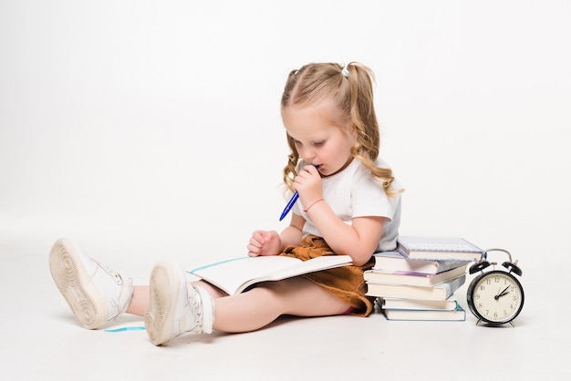 Adorable cute little girl writing drawing in notebook sitting on the floor isolated