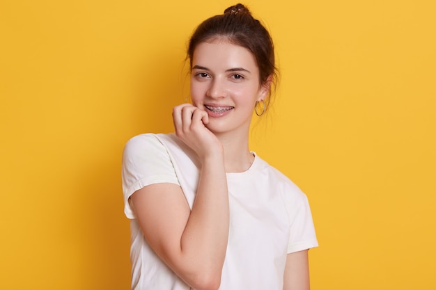 Adorable dark haired young woman in brackets looking at camera with charming smile