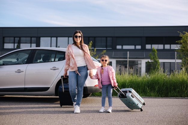 Adorable daughter with her mom go to airport with suitcases two girls goes to a trip little girl