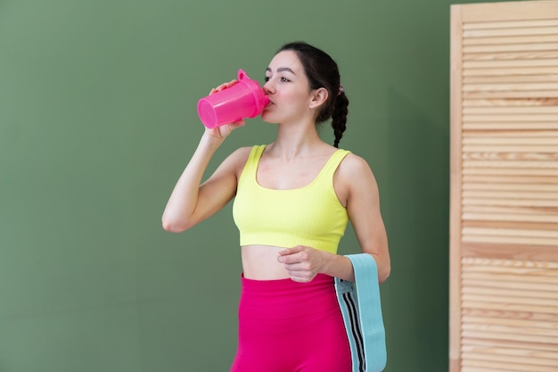 Adorabile donna in forma che beve dalla bottiglia d'acqua dopo l'allenamento sportivo