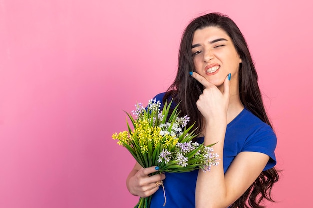 Adorable girl blinking an eye and holding bunch of flowers High quality photo