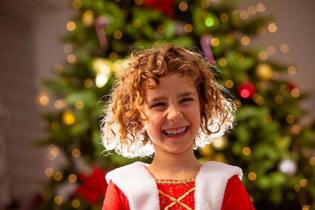 클래식 장식된 크리스마스 트리 근처 크리스마스 드레스에 사랑스러운 소녀