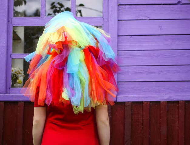 Adorable girl in colorful rainbow dress on her head playing\
outdoors