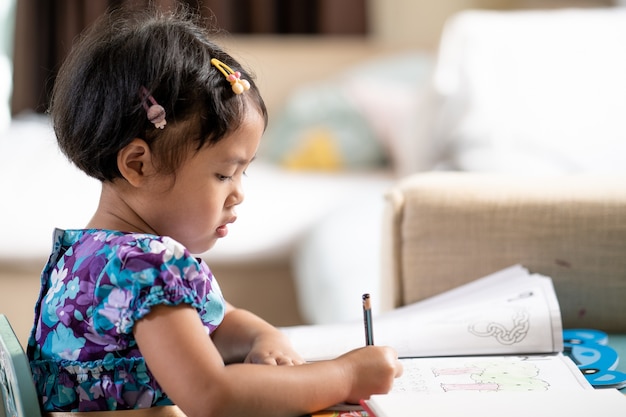 Adorable girl doing homework at table indoor