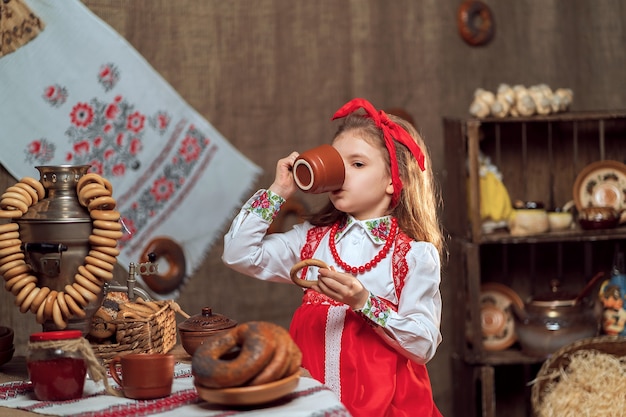 Photo adorable girl drinking tea from samovar