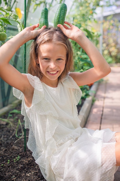 Adorable girl having fun in greenhouse portrait of kid with basket with vegetables