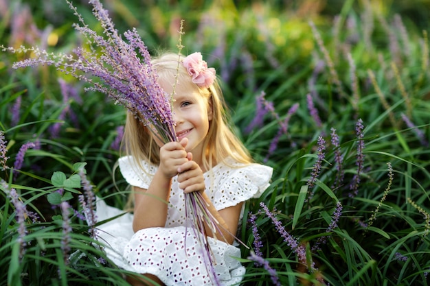 Adorable girl holding flowers in park.