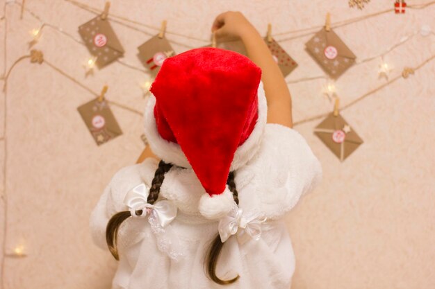 Adorable girl looks at the creative handmade Christmas advent calendar.