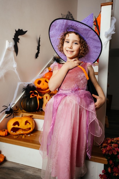 Adorable girl posing in pink dress and witch hat