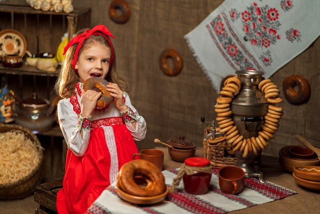 Фото Очаровательная девушка сидит за столом, полным еды и большого самовара тра