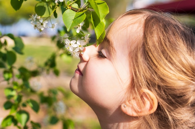 Adorable girl smelling flowers close up