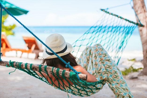 Adorable girl on tropical vacation relaxing in hammock