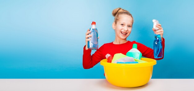 Adorable girl with a basin full of cleaners