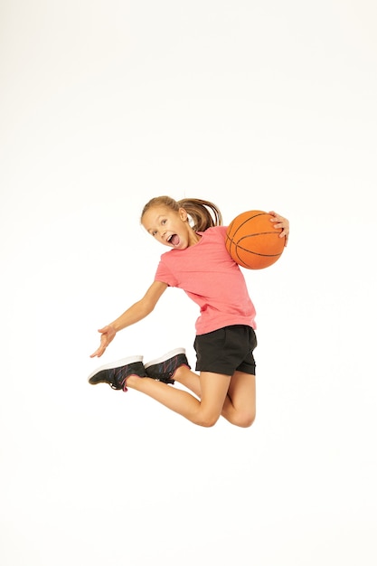 농구공이 점프하고 기쁨으로 비명을 지르는 사랑스러운 소녀