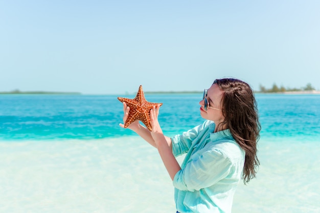 Adorable girl with starfish on the beach