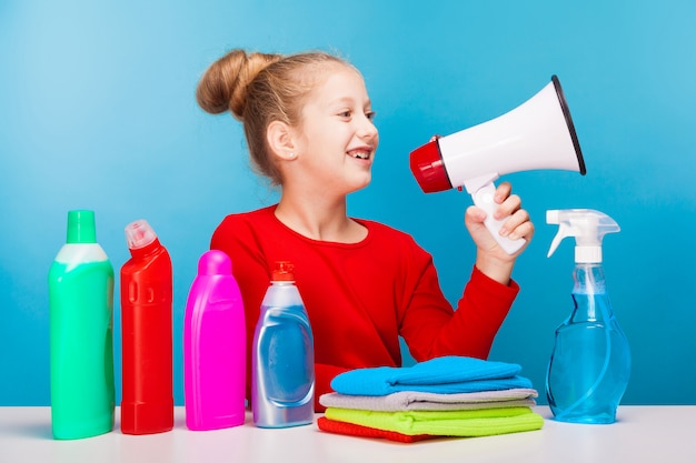 Adorable girl with various cleaners holding a speaker