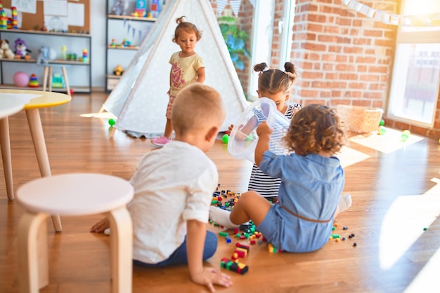 Adorable group of toddlers playing around lots of toys at kindergarten