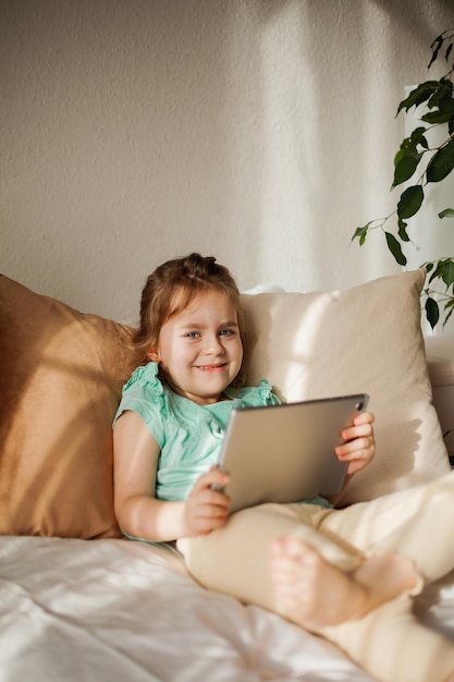 Photo adorable happy child playing with tablet online assignments and lessons