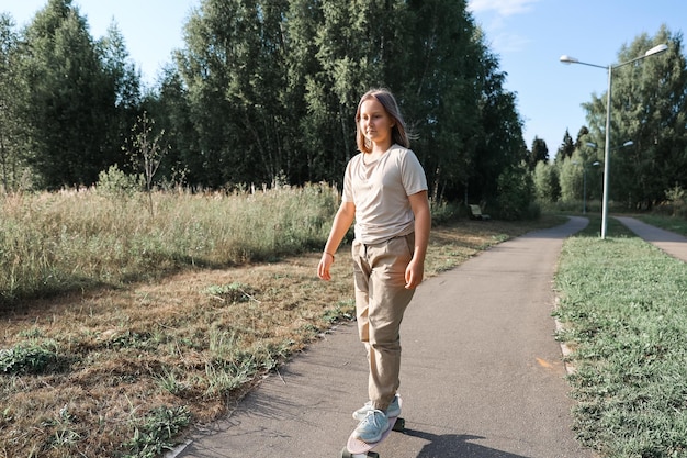 Adorable happy girl riding skateboard in park