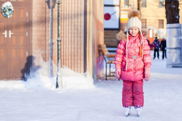 Adorable happy little girl enjoying skating at the ice-rink